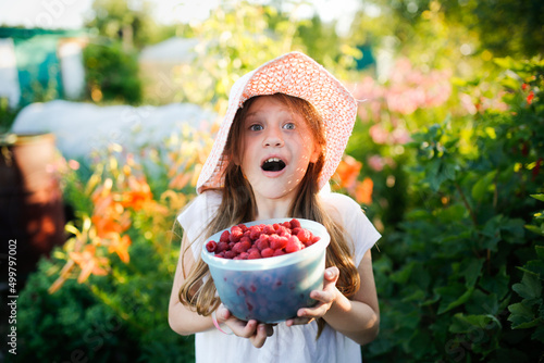 Fotografia Cute European girl child teenager with big bowl of raspberries, Daughter helps p