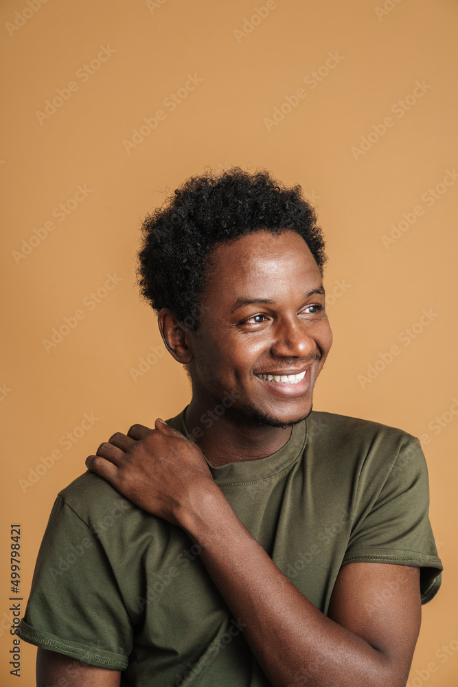 Young black man wearing t-shirt smiling and looking aside Young black man wearing t-shirt smiling and looking aside