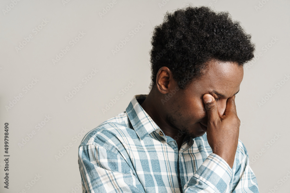 Black unshaven man in plaid shirt posing while covering her eyes Black unshaven man in plaid shirt posing while covering her eyes