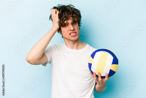 Young caucasian man playing volleyball isolated on blue background being shocked, she has remembered important meeting.