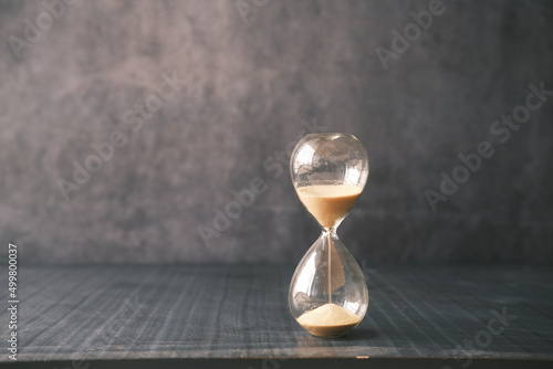 Obraz na plátně hourglass on table, sand flowing through the bulb of sandglass