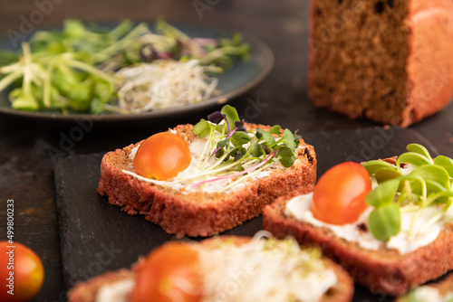 Red beet bread sandwiches with cream cheese, tomatoes and microgreen on black. side view, selective focus.