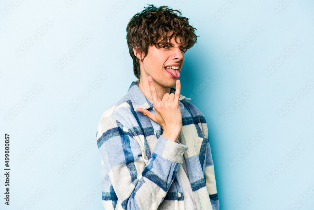 Fototapeta premium Young caucasian man isolated on blue background showing rock gesture with fingers