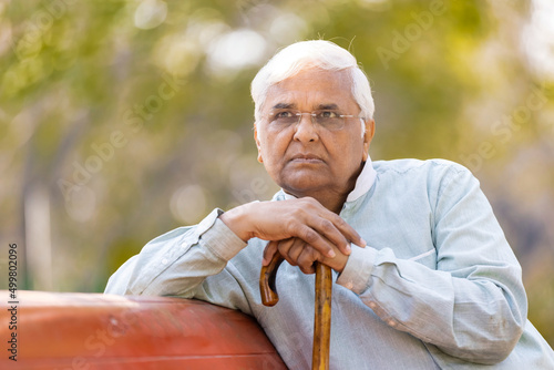Canvas Print Thoughtful senior man at park with walking cane