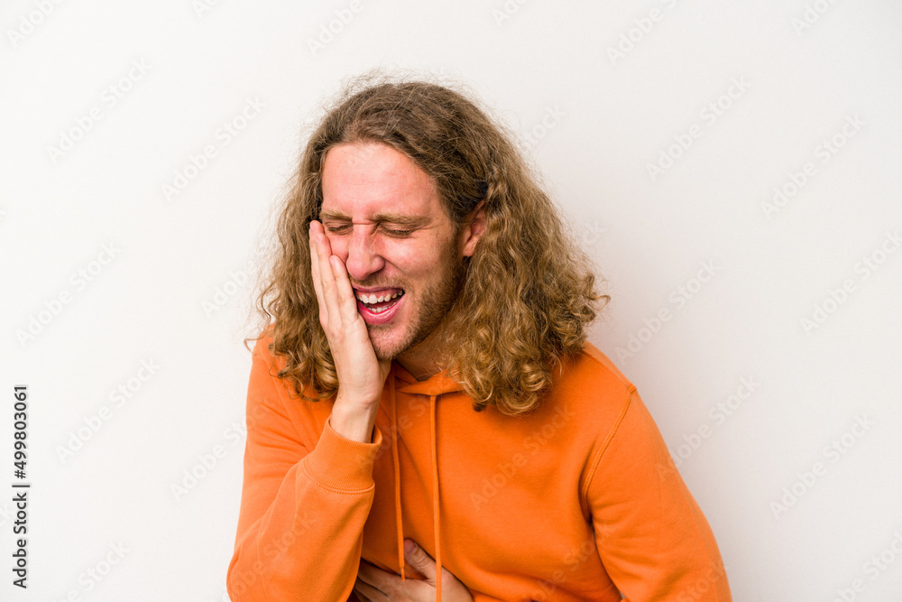 Young caucasian man isolated on white background laughs happily and has fun keeping hands on stomach. Young caucasian man isolated on white background laughs happily and has fun keeping hands on stomach.