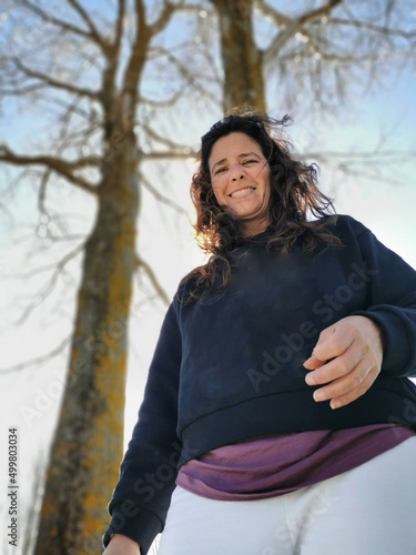 Valokuva Backlit and contrapposto portrait of a smiling middle-aged woman