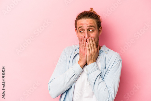 Young caucasian man isolated on pink background laughing about something  covering mouth with hands.
