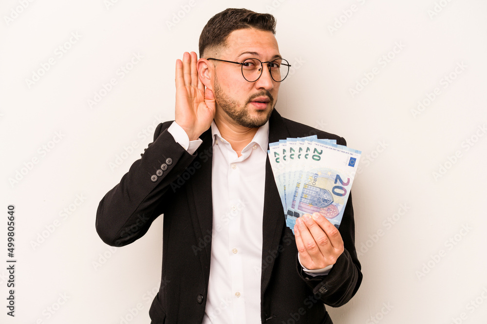 Business hispanic man holding banknotes isolated on white background trying to listening a gossip. Business hispanic man holding banknotes isolated on white background trying to listening a gossip.