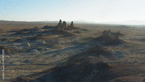 High and smooth establishing shot of the Pinnacles in the desert with a mountain range yonder at sunset photo