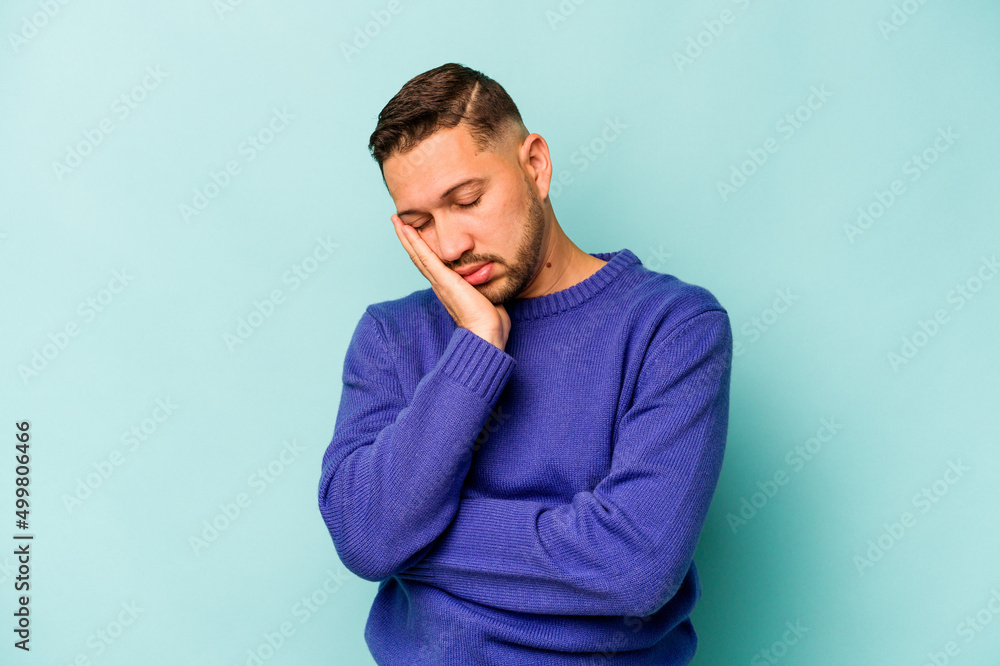 Young hispanic man isolated on blue background who is bored, fatigued and need a relax day. Young hispanic man isolated on blue background who is bored, fatigued and need a relax day.