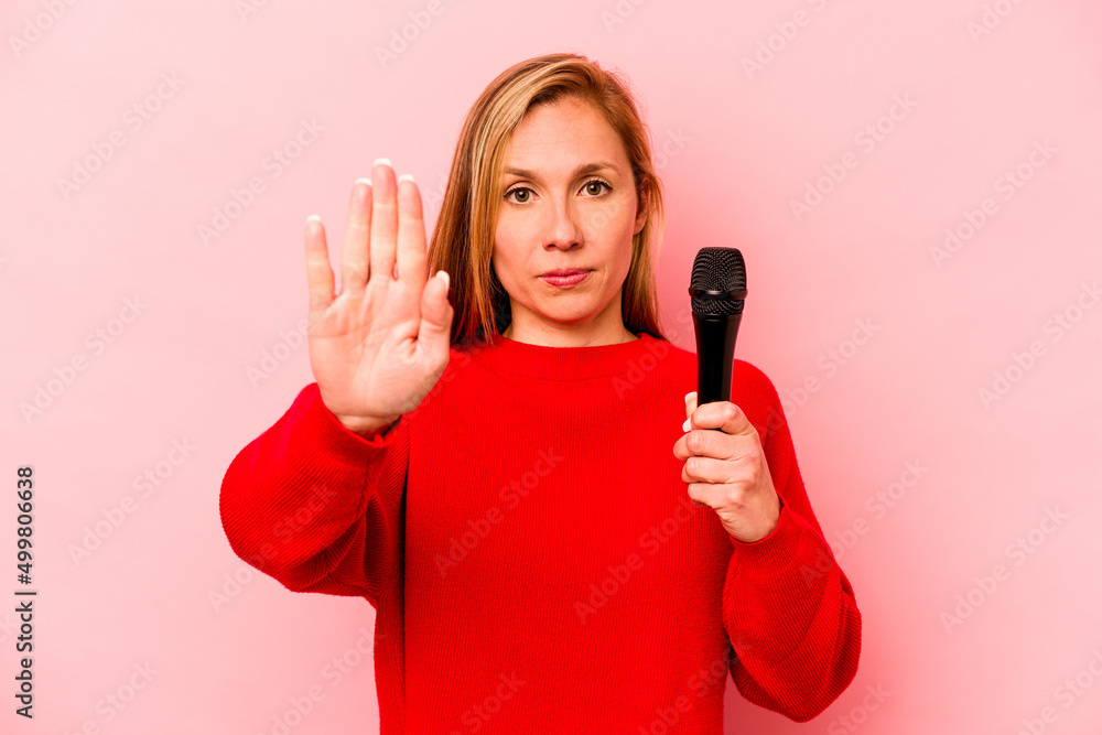 Young caucasian singer woman isolated on pink background standing with outstretched hand showing stop sign, preventing you. Young caucasian singer woman isolated on pink background standing with outstretched hand showing stop sign, preventing you.