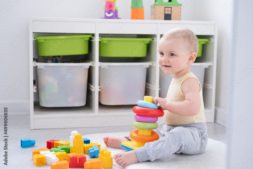 Cute baby girl playing in colorful pyramid on floor at home. Early childhood development Cute baby girl playing in colorful pyramid on floor at home. Early childhood development