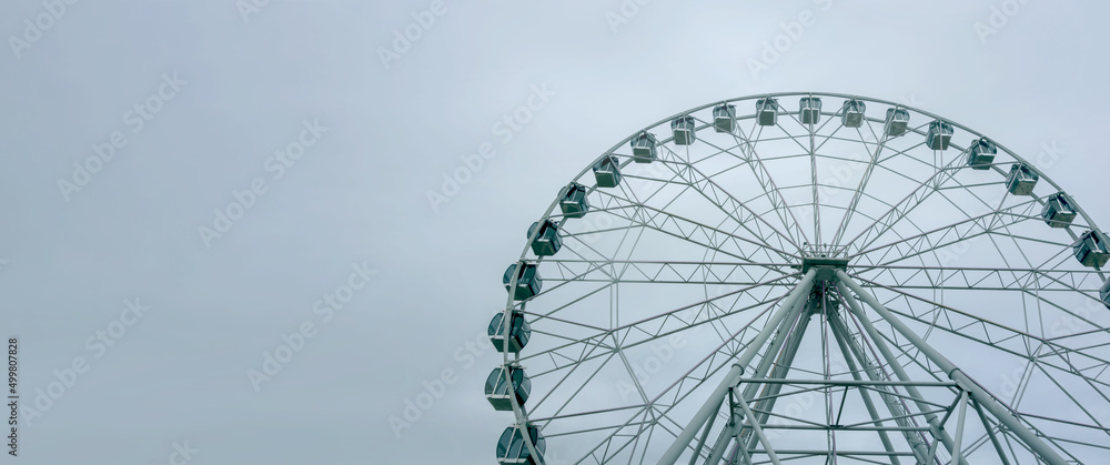City park with a view of the Ferris Wheel attraction on a spring day, close-up. City park with a view of the Ferris Wheel attraction on a spring day, close-up.