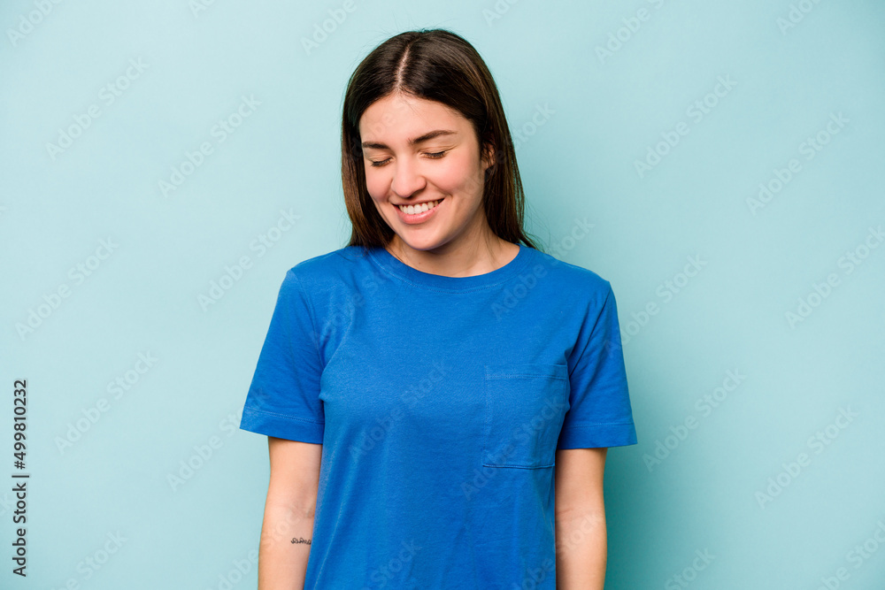 Obraz premium Young caucasian woman isolated on blue background laughs and closes eyes, feels relaxed and happy.