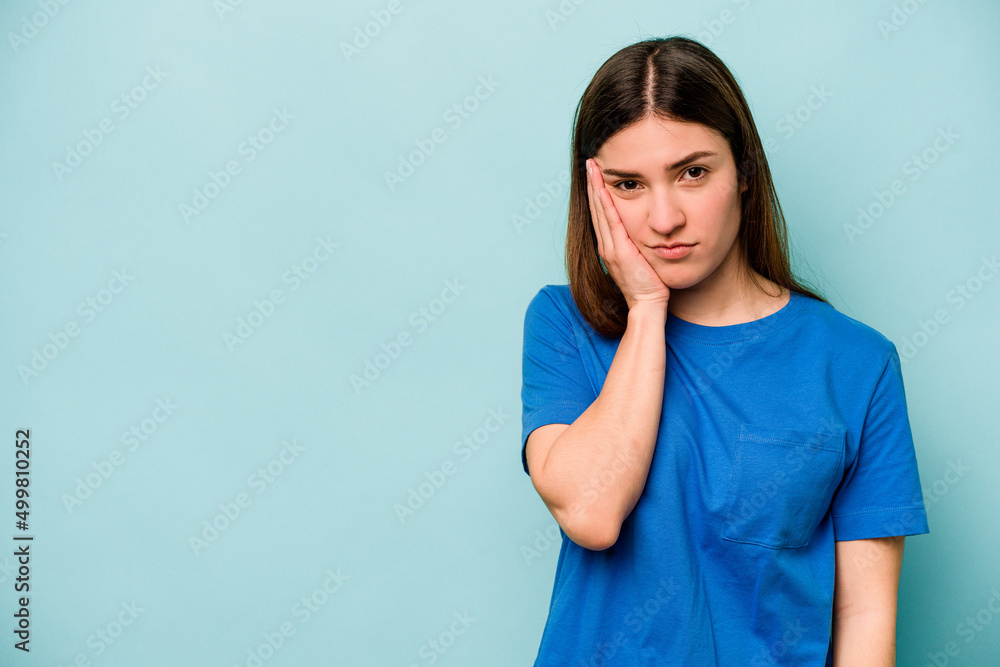 Young caucasian woman isolated on blue background who feels sad and pensive, looking at copy space. Young caucasian woman isolated on blue background who feels sad and pensive, looking at copy space.