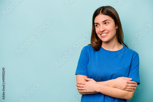 Young caucasian woman isolated on blue background smiling confident with crossed arms.