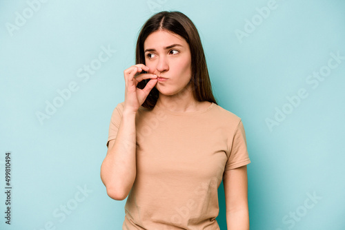 Young caucasian woman isolated on blue background with fingers on lips keeping a secret.