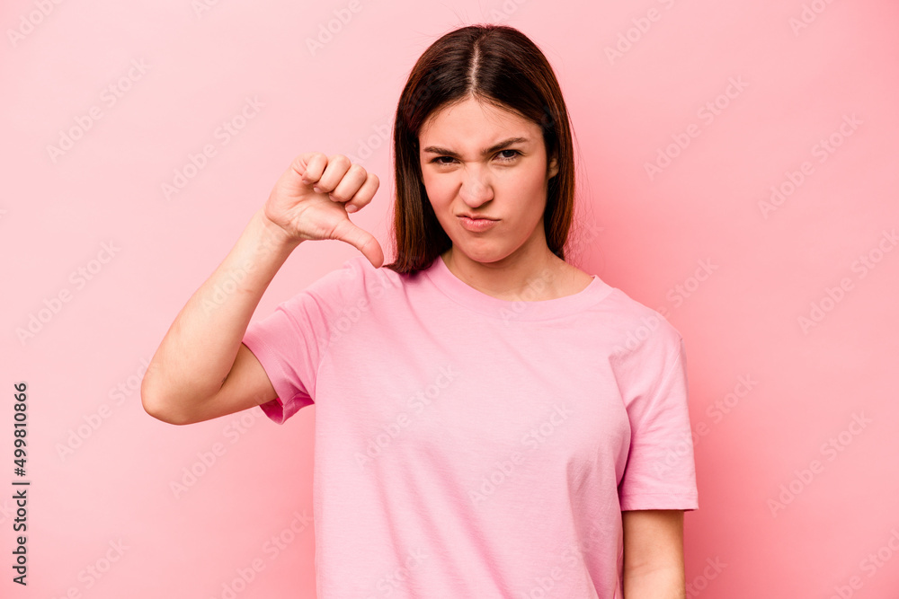 Young caucasian woman isolated on pink background showing thumb down and expressing dislike. Young caucasian woman isolated on pink background showing thumb down and expressing dislike.