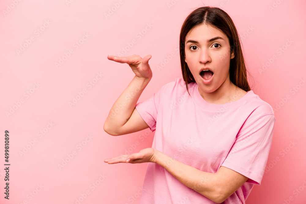 Young caucasian woman isolated on pink background shocked and amazed holding a copy space between hands. Young caucasian woman isolated on pink background shocked and amazed holding a copy space between hands.