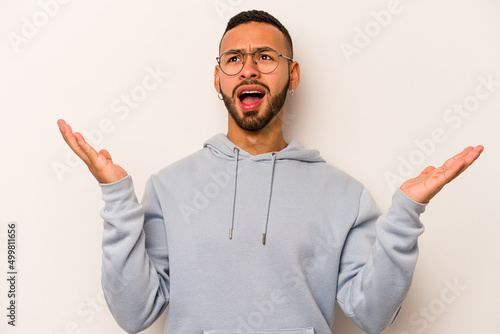 Young hispanic man isolated on white background screaming to the sky, looking up, frustrated.