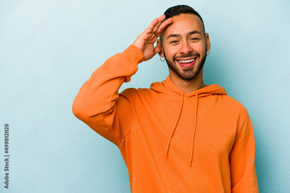 Young hispanic man isolated on blue background shouts loud, keeps eyes opened and hands tense. Young hispanic man isolated on blue background shouts loud, keeps eyes opened and hands tense.