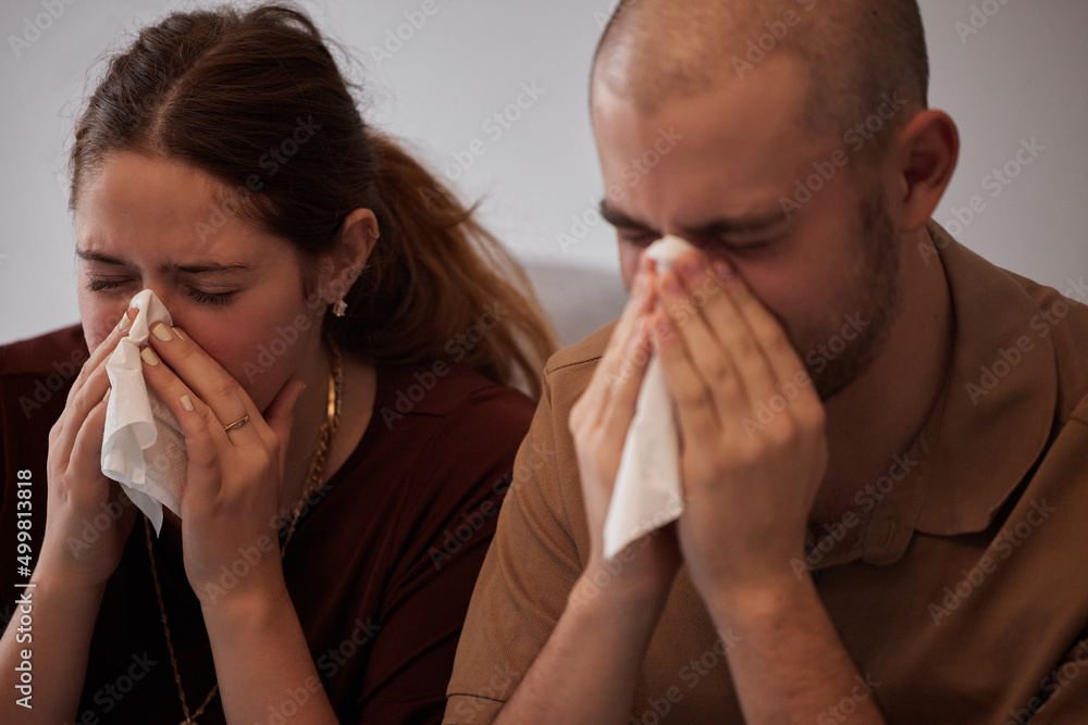 At least were sick together. Shot of a young couple blowing their noses during a cold. At least were sick together. Shot of a young couple blowing their noses during a cold.