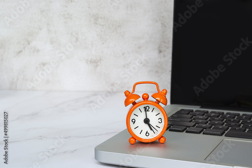Alarm clock isolated on laptop or notebook. The clock set at 5 o'clock. photo