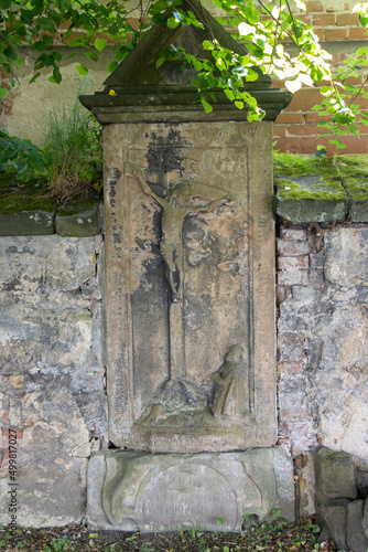 Photo A baroque tombstone with crucified Jesus in the wall of cemetery