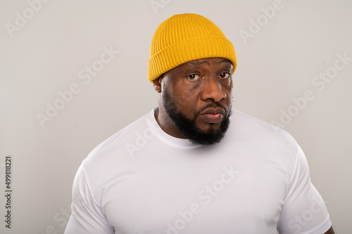 Headshot portrait of a Nigerian man wearing a  yellow beanie hat on a white background with space for copy 