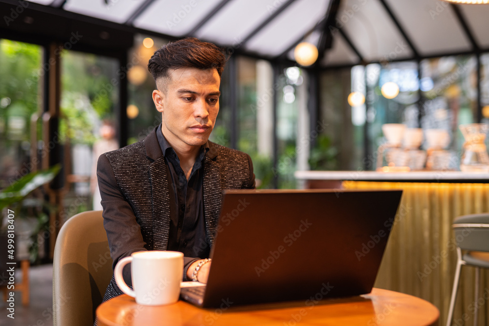 Portrait of handsome young businessman using laptop in coffee shop Portrait of handsome young businessman using laptop in coffee shop