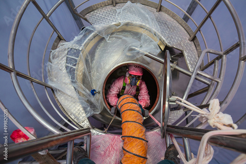 Top view male worker climb up the stairs into the tank stainless chemical area confined space photo