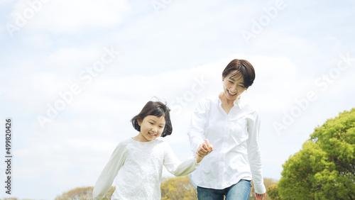 手を繋いで草原を歩く母娘 ファミリー 子育て 自然環境