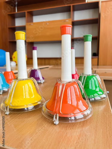 Multicolored hand bells on the wooden background. Musical instrument. School music lessons.
