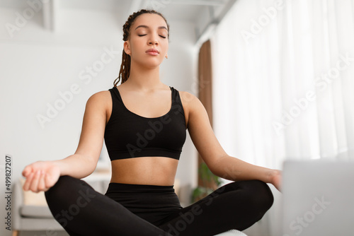 Calm African American Woman Meditating Sitting Doing Yoga At Home