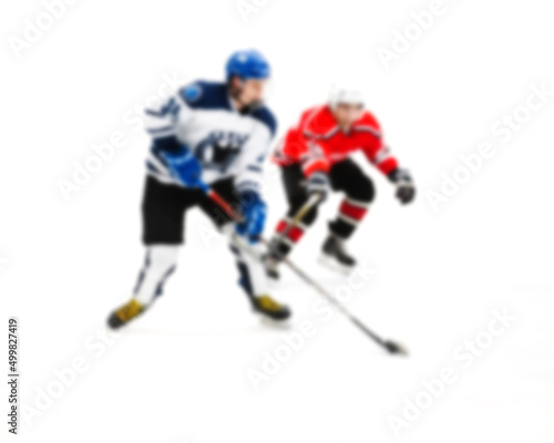 Fototapeta Naklejka Na Ścianę i Meble -  Rival hockey players fight for control of the puck - out of focus hockey player on ice - blur hockey match on background