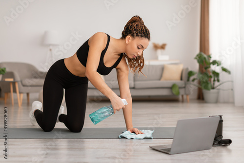 Black Female Cleaning Gymnastics Mat Using Detergent Before Workout Indoors