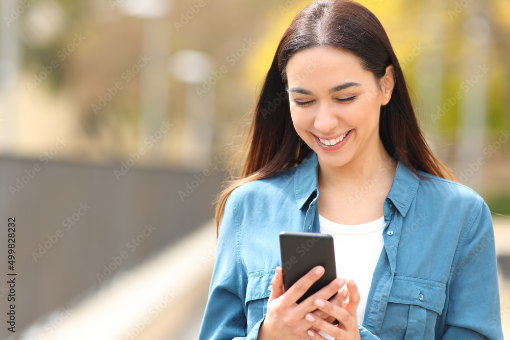 Happy woman walks using smart phone in the street Happy woman walks using smart phone in the street