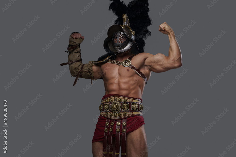 Shot of handsome greek warrior with nude muscular body showing his strength against grey background. Shot of handsome greek warrior with nude muscular body showing his strength against grey background.