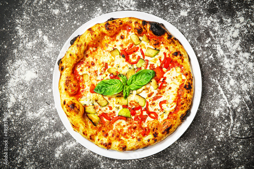 Top view of vegetarian pizza with zucchini and pepper on dark background.