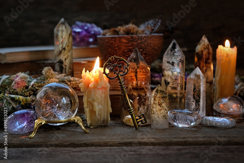 Foto Candles, crystal ball, key, gemstones, magic things on dark wooden background