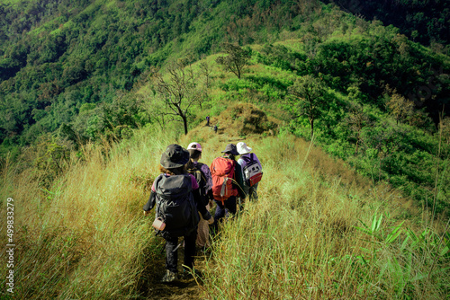 Group of hiking with heavy backpack bag adventure trekking to the top of the mountain at sunset coulds sky. Journey life travelling lifestyle and sport activity.