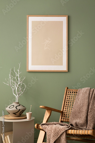 Fototapeta Naklejka Na Ścianę i Meble -  Stylish living room interior design with mock up poster frames, rattan armchair, coffe table, beige carpet and creative home accessories. Sage green wall. Template.