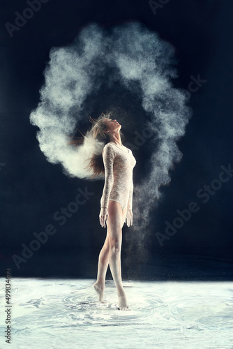 Studio muse. Studio shot of a young woman leaving a trail of powder in the air by whipping her hair.