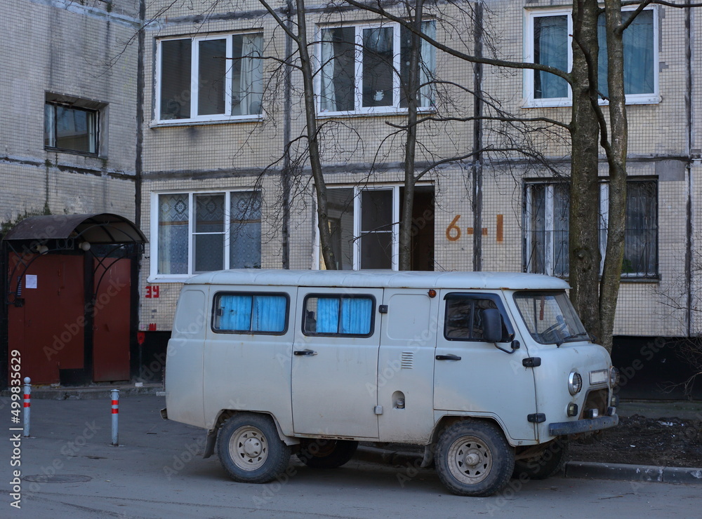 A grey Russian minivan is parked in the courtyard of a residential building, Solidarity Avenue, St. Petersburg, Russia, April 2022