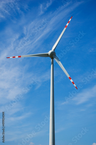 Windmill for electric power production against blue sky.