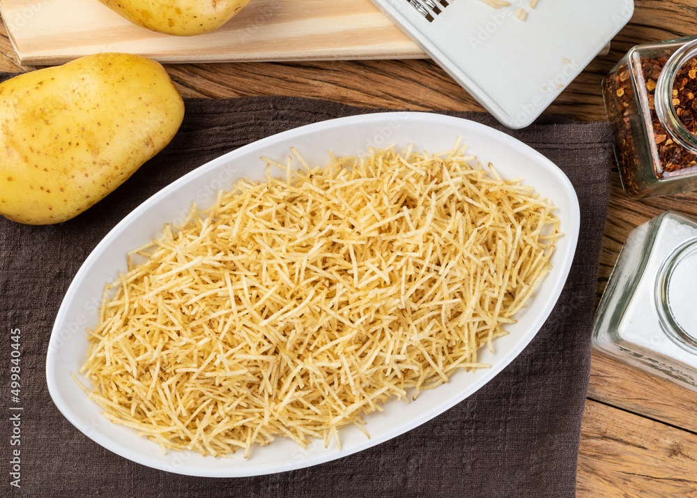 Potato straw or shoestring potato in a white plate with raw potatoes Potato straw or shoestring potato in a white plate with raw potatoes