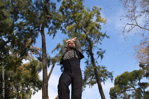 gypsy man with long hair dancing flamenco on an open air stage in a park in seville and he is doing different postures with a lot of passion. Flamenco dance concept cultural heritage of humanity.