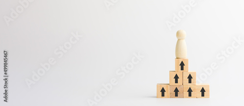 Leadership and business concept. The wooden figure stands on a stack of wooden blocks with the upper arrow. Succesful competition, winner, creative and management.