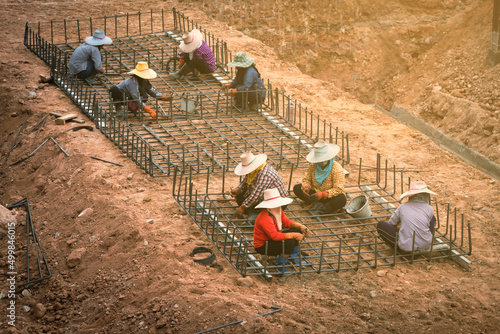 Thai workers hands using iron wire for securing iron bars . 