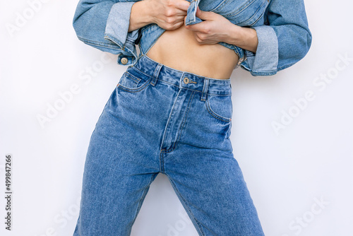 Cropped shot of young slender woman in a fashionable blue jeans with a high fit isolated on a white background. Beauty and fashion concept photo